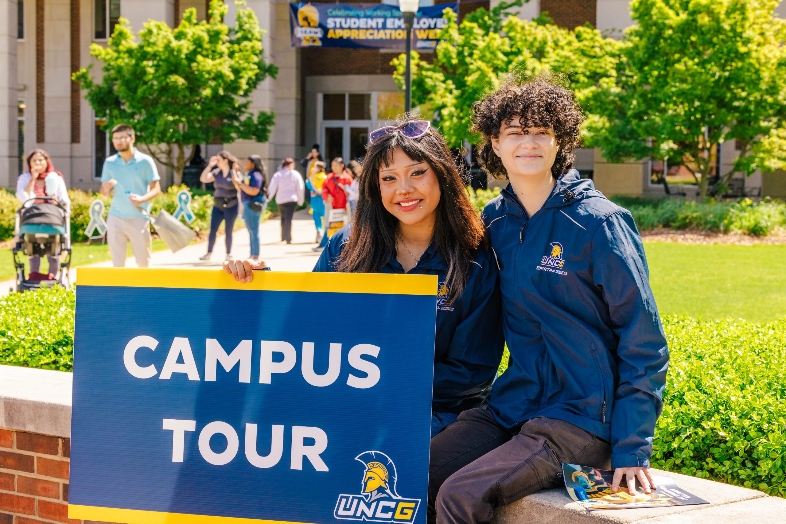 Two student guides hold up a sign reading "campus tours."
